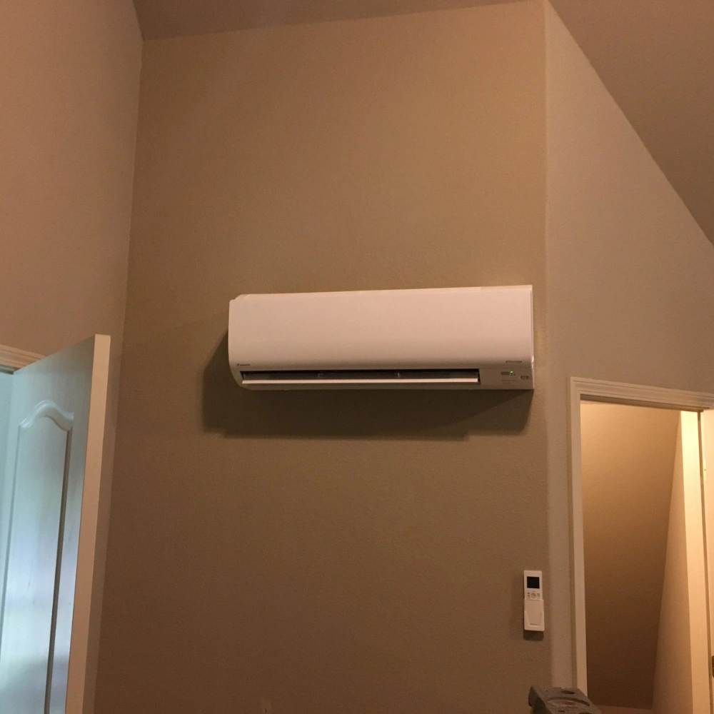 Wall-mounted air conditioner in a beige room, above a door slightly ajar. 
