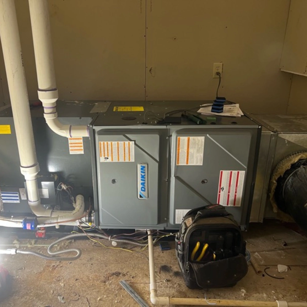 A gray HVAC unit labeled "Daikin" is surrounded by white pipes and wiring. 