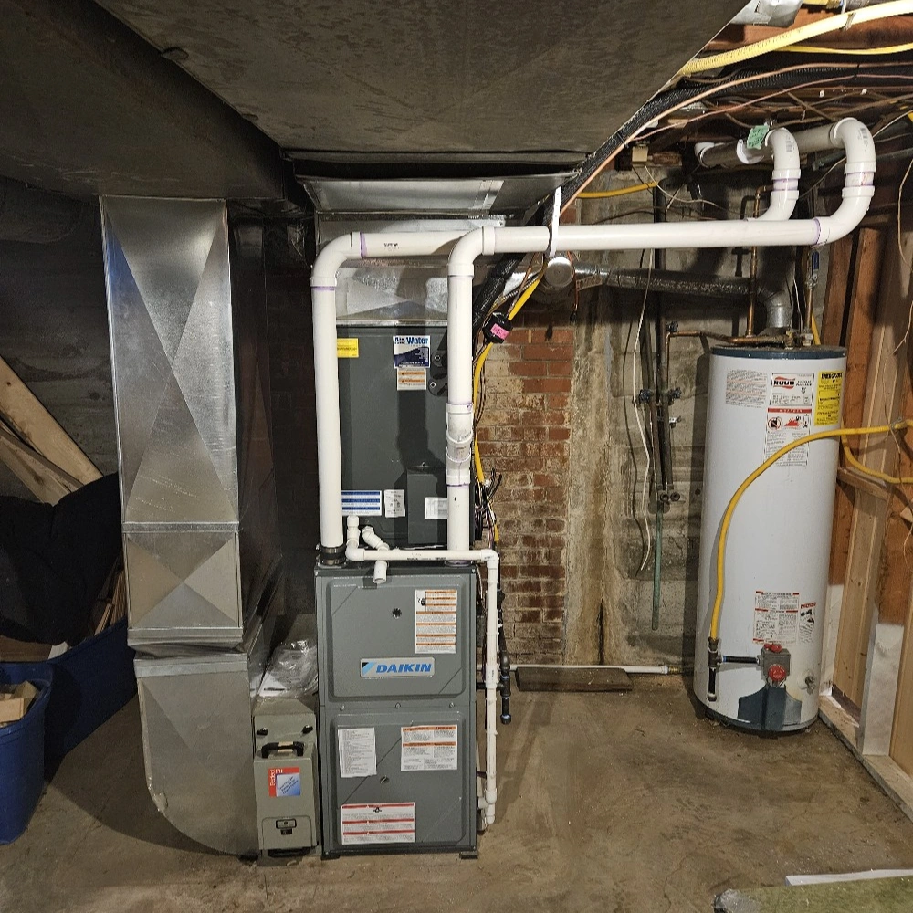 Basement with a gray HVAC unit and ducts, adjacent to a white water heater. 
