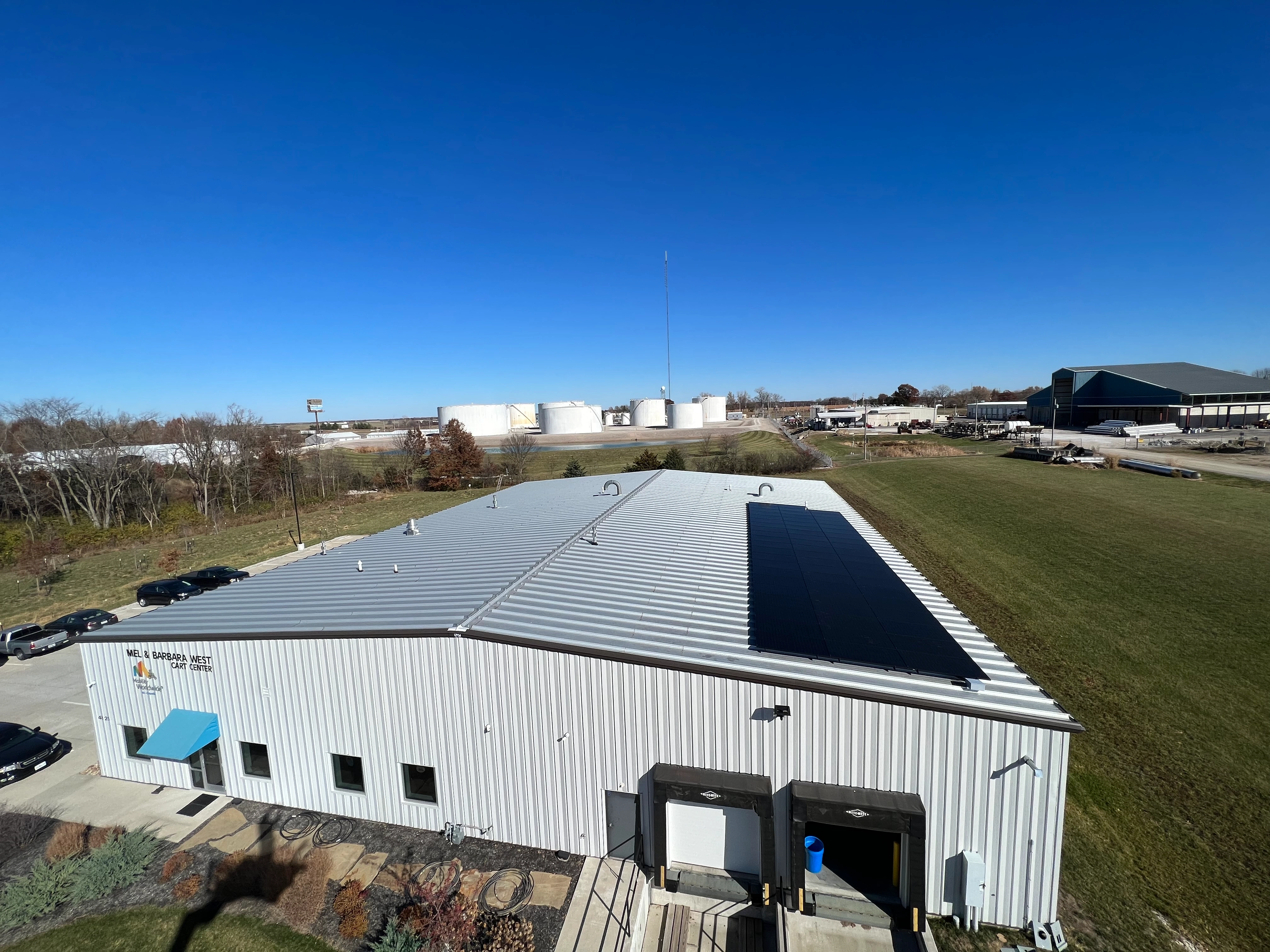 Aerial view of a white industrial building with a solar panel array on its roof.