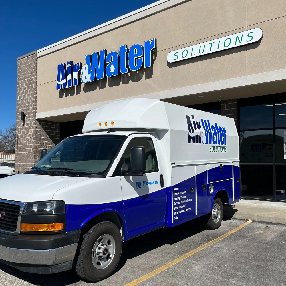 A white and blue service van is parked in front of an "Air & Water Solutions" store, with clear blue skies. 