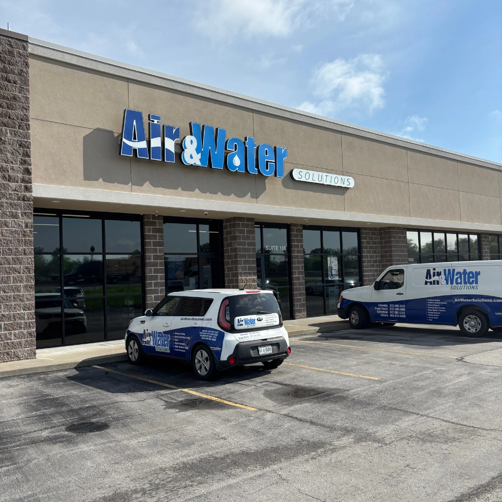 Storefront of "Air & Water Solutions" with branded vehicles in front, including a car and van. 