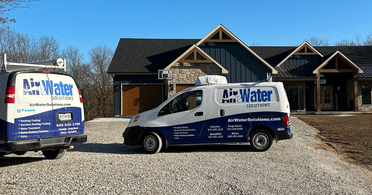 Two Air & Water Solutions service vans parked in front of a home