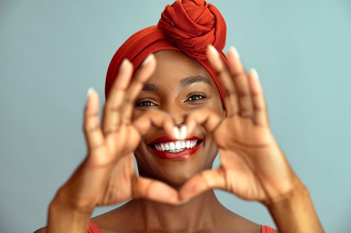 Patient smiling as his grin is framed by heart-shaped hands formed with a dentist.