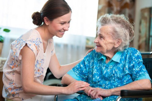 Young woman helping elderly woman in her wheelchair
