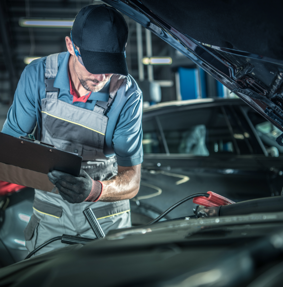 Technician diagnosing a car and holding a clipboard.