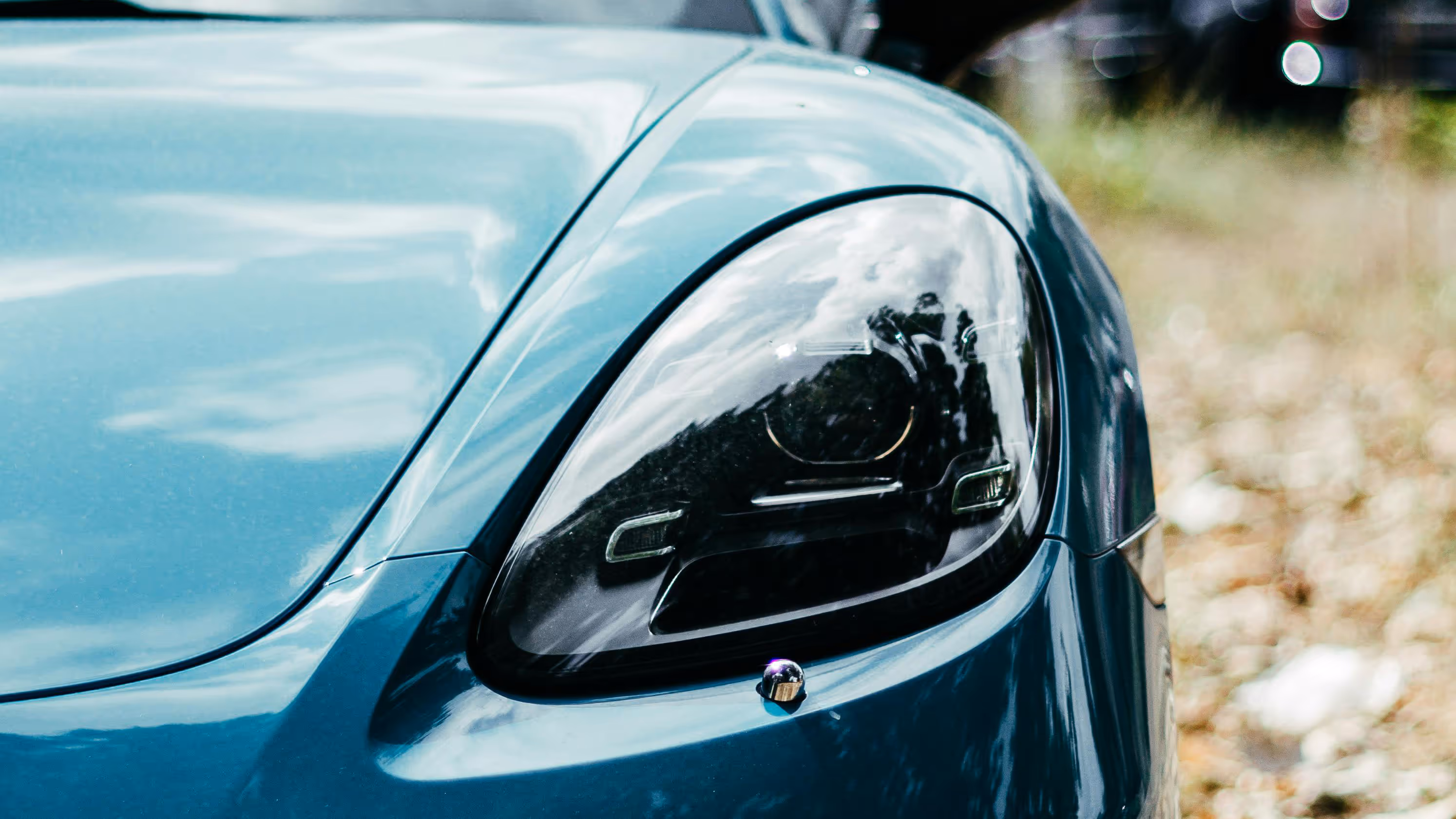 A close-up of a blue car's driver side headlight.