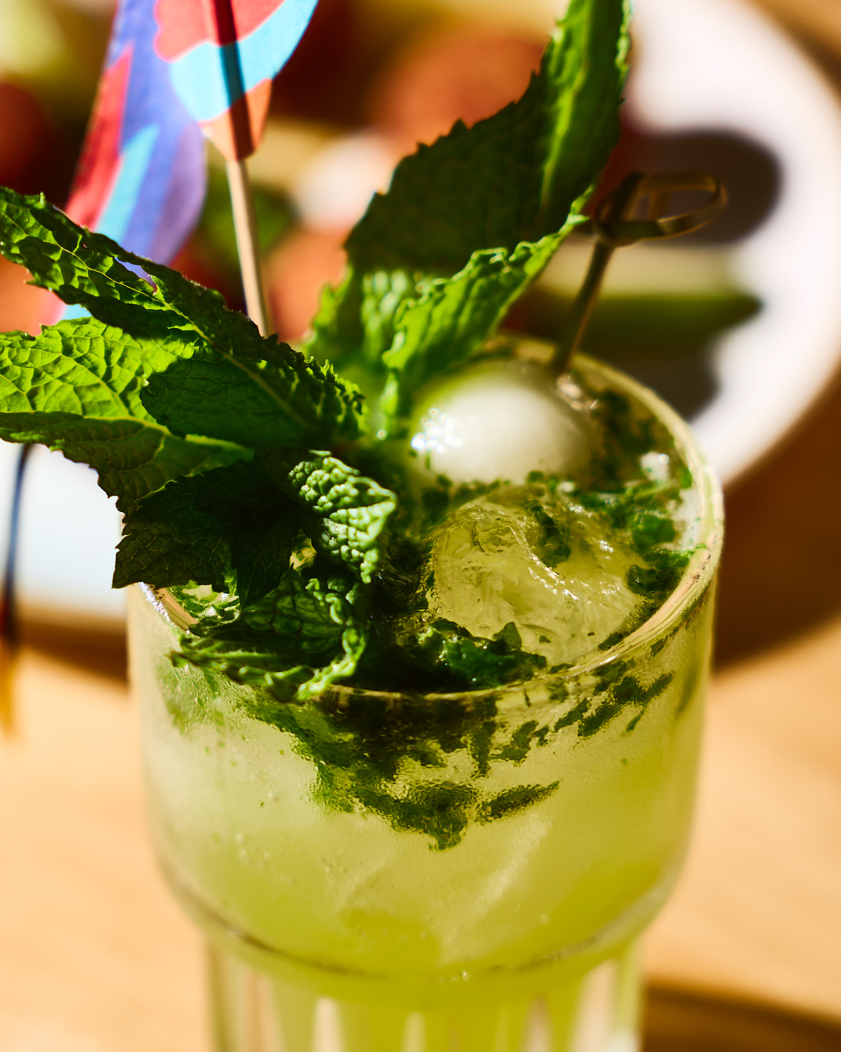Close-up of a green mint cocktail with crushed ice and fresh mint leaves in a clear glass.