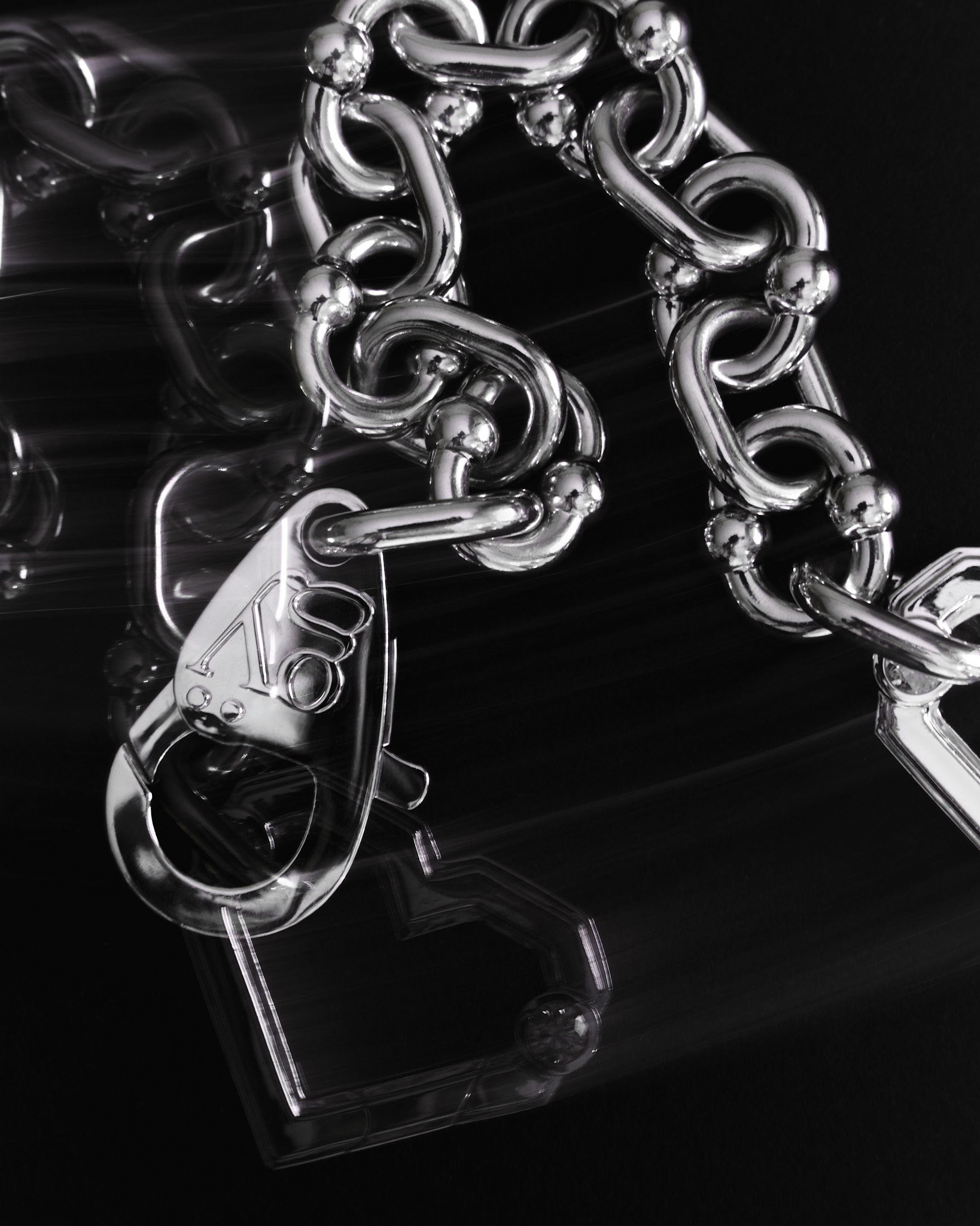 Close-up of a shiny silver chain bracelet with a heart-shaped clasp on a black background.