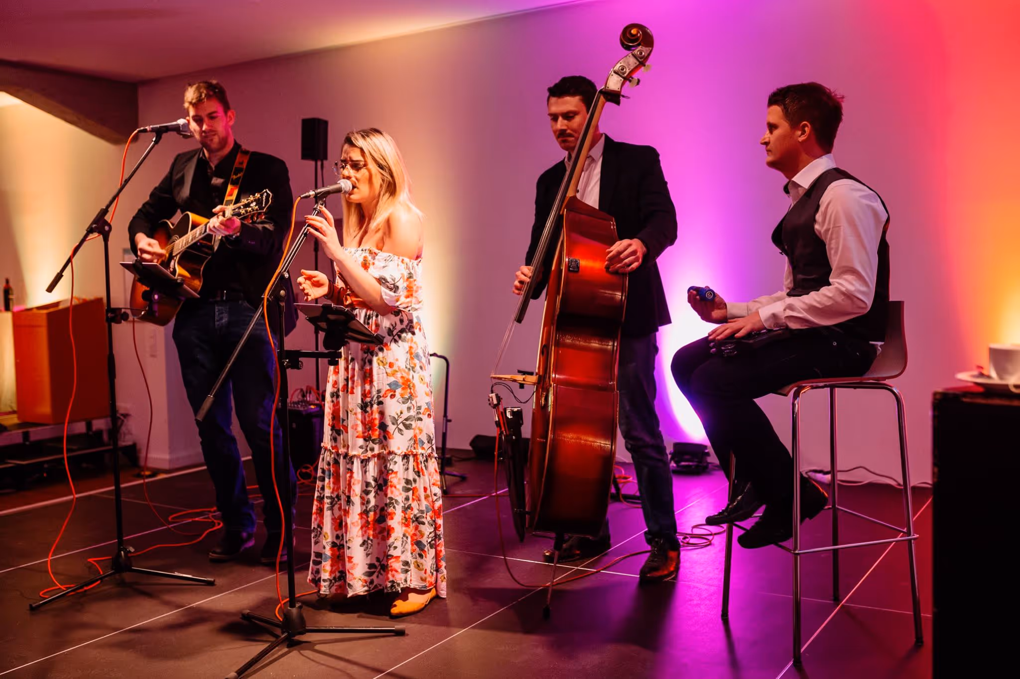 A group of people dressed in cultural or formal attire are standing on a stage with musical instruments, possibly performing or giving a presentation.
