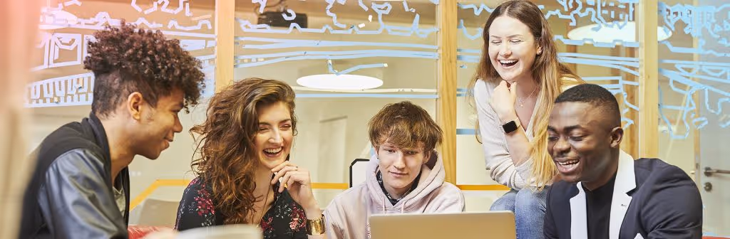 A group of students smiling and posing together for a fun, candid photo in a study or common area.