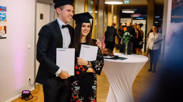 A group of people in business attire standing and mingling at a professional networking or school event.