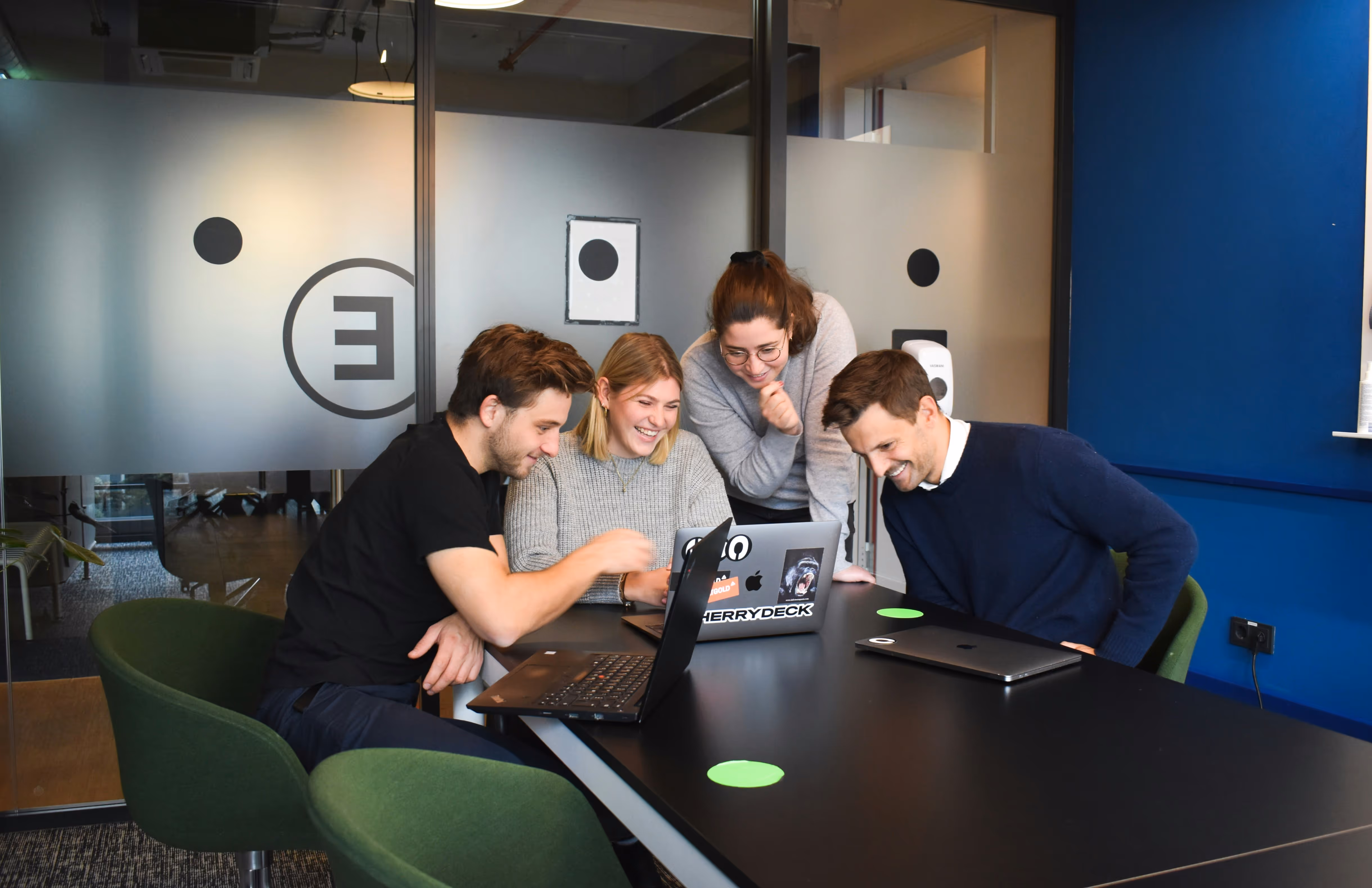Group of young people working together on their laptop in an office, laughing