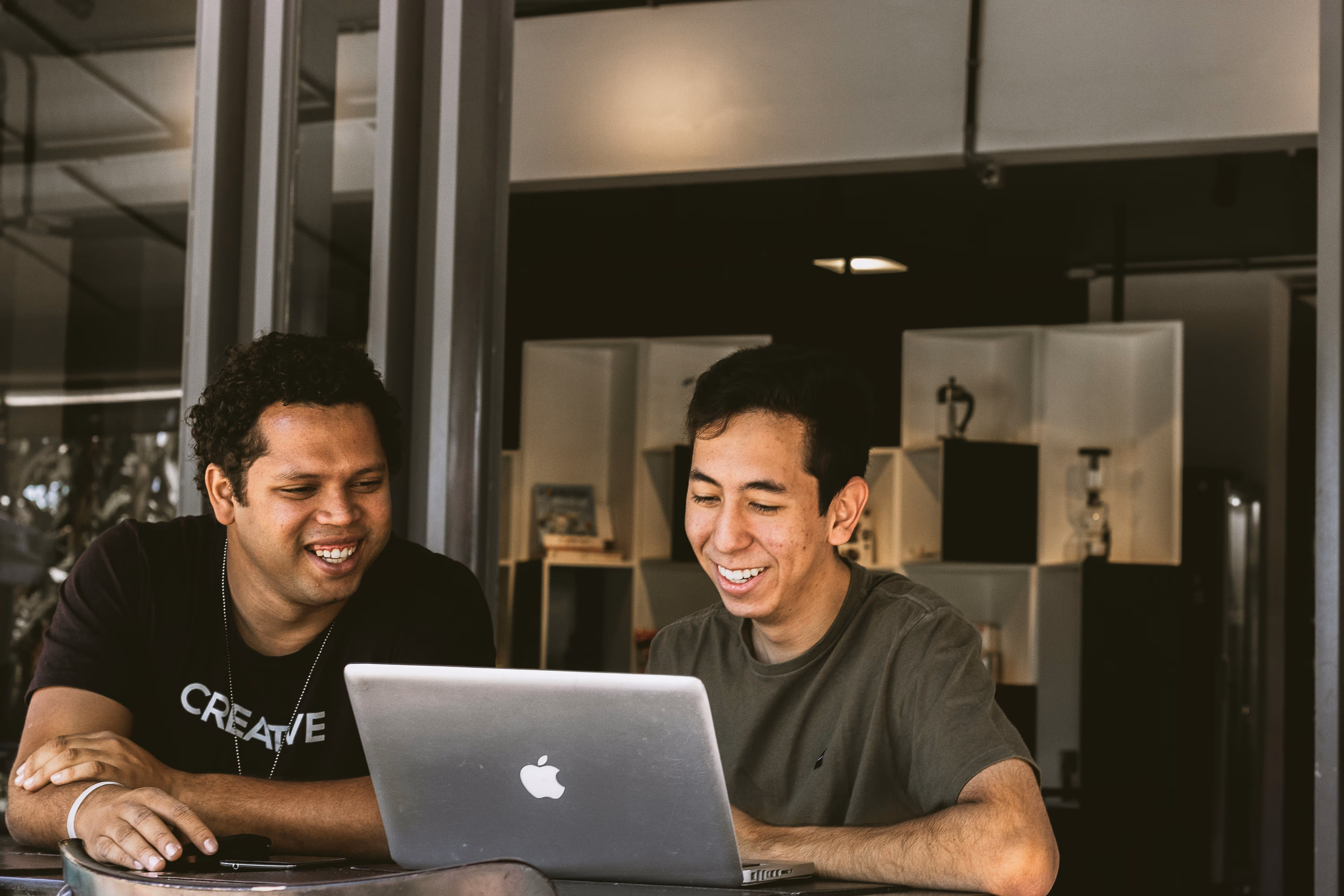 Two men looking at a laptop and laughing