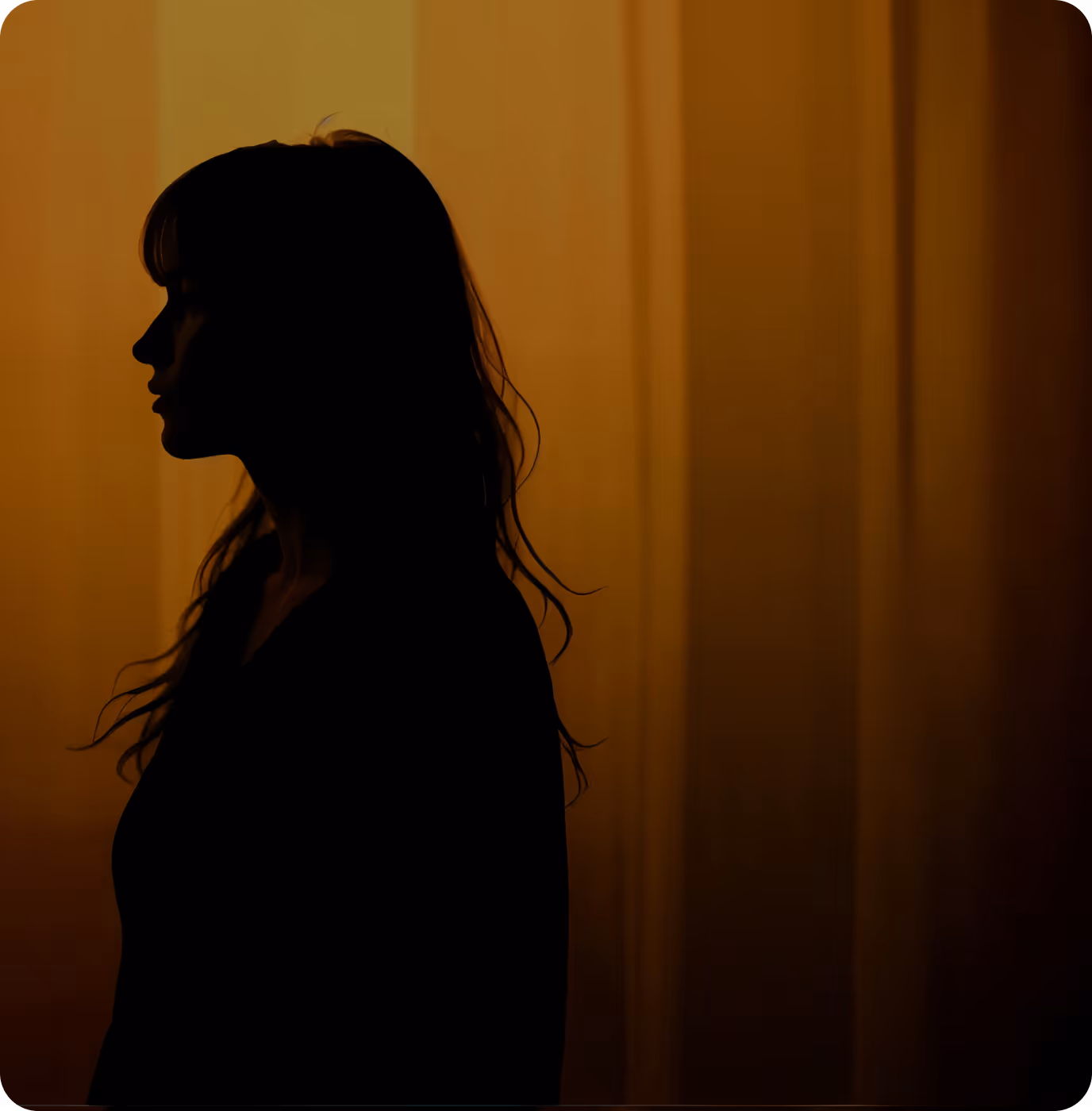 A silhouette of a woman standing in front of a curtain.