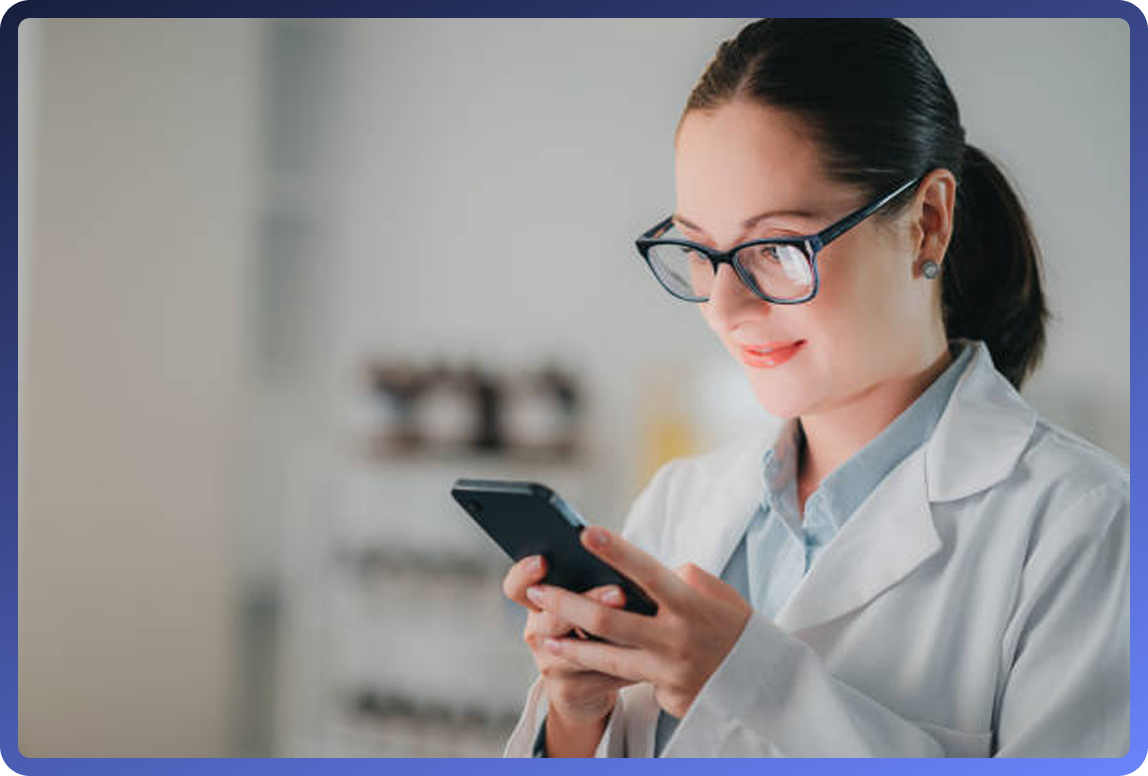 Female healthcare professional in white coat and glasses reviewing information on her phone