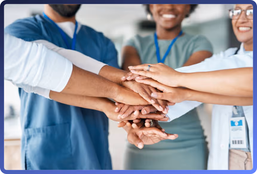 Group of healthcare professionals placing their hands together in a circle to signify teamwork