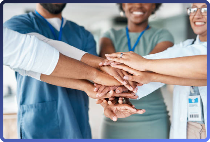 Group of healthcare professionals placing their hands together in a circle to signify teamwork