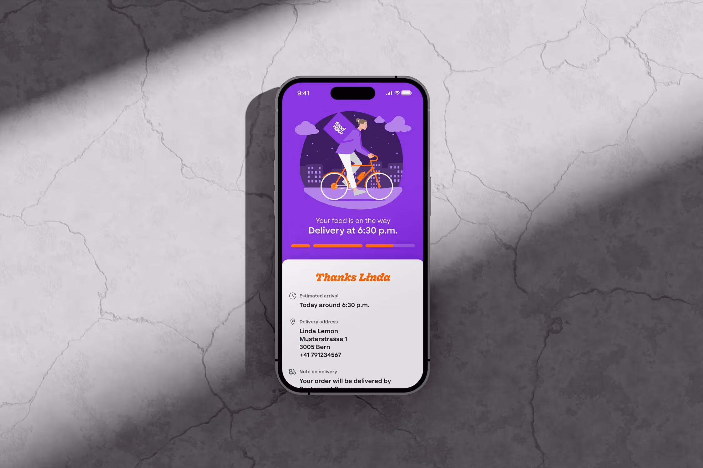 Smartphone on cracked gray surface showing food delivery app with a cyclist illustration and delivery details to Linda Lemon.