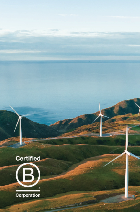 Wind turbines on grassy hills by the sea with a "Certified B Corporation" logo in the foreground.