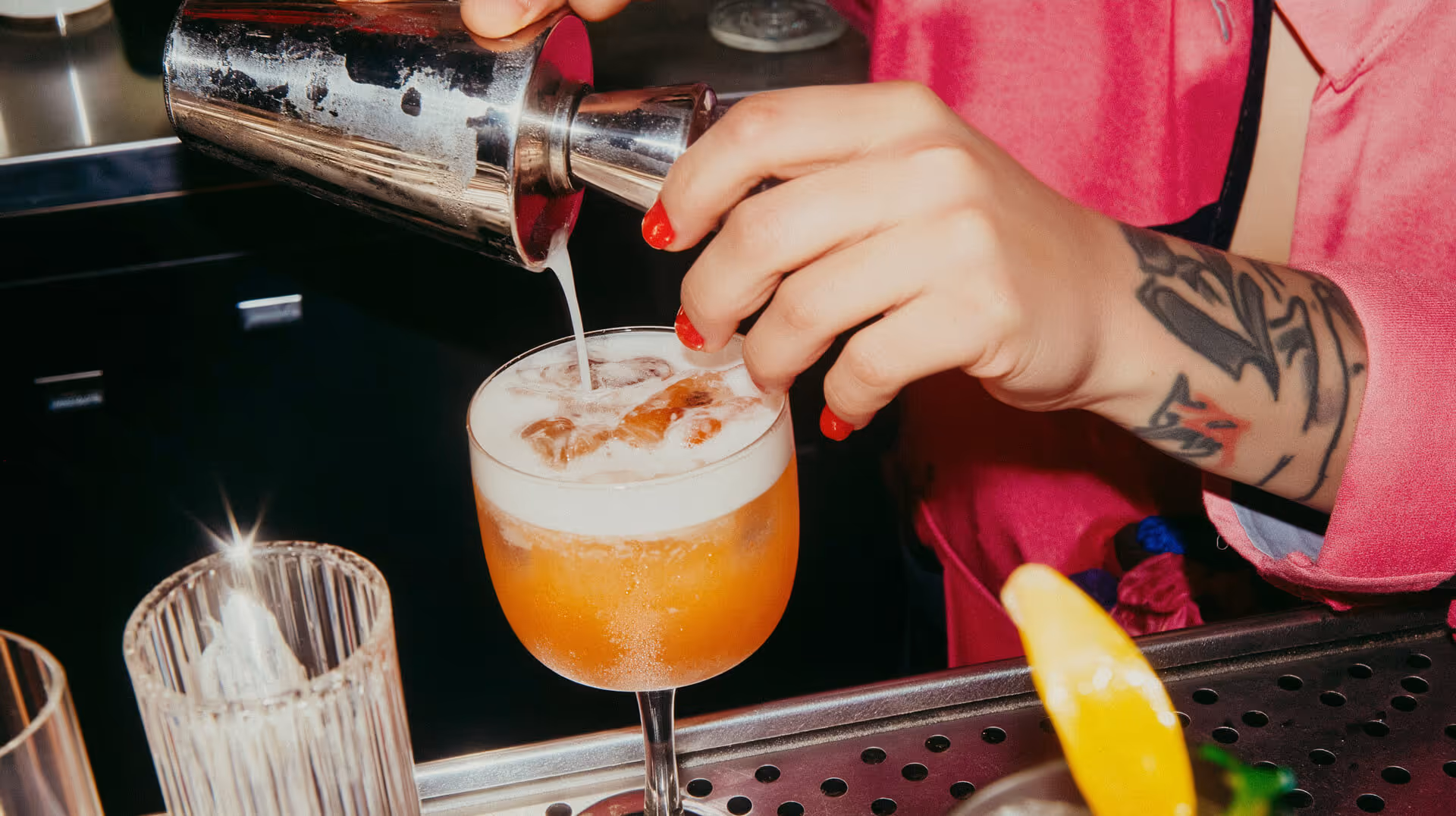 Eine Barkeeperin steht hinter der Lobbybar des Hotel 6000 in Luzern und mixt einen Cocktail, umgeben von modernem Interieur und warmem Ambientelicht.