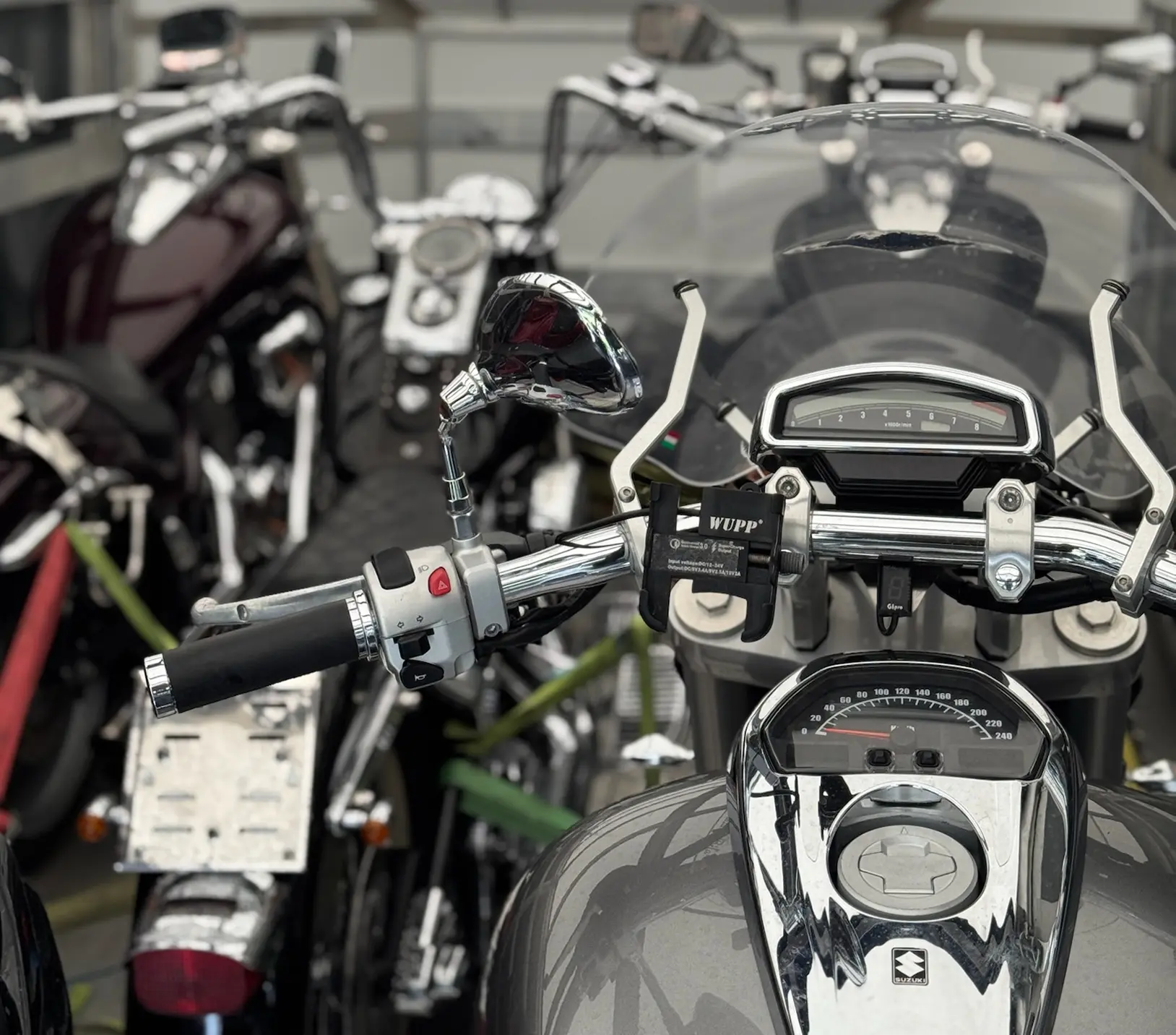 Egy szürke motor kormánya és tankja a fókuszban, ahogy épp szállítják. 