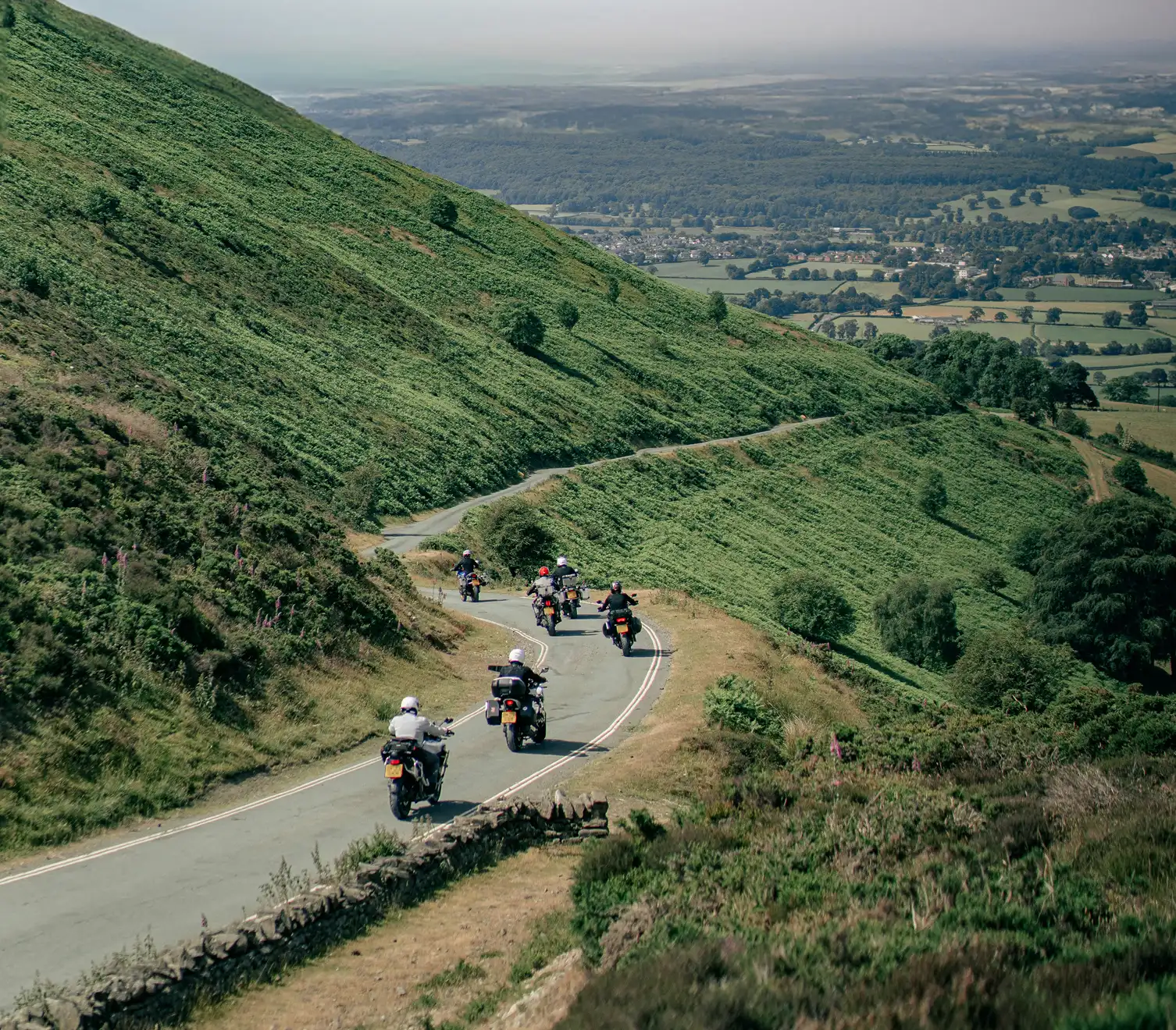 Motoros csoport halad át a zöld hegyen átvezető úton