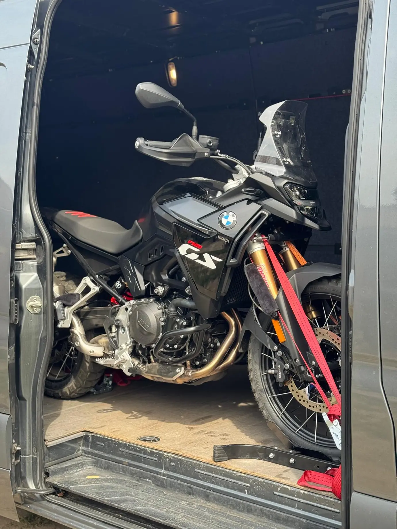 A kisteherautó nyitott ajtójánál látható egy biztonságosan rögzített fekete motor. 