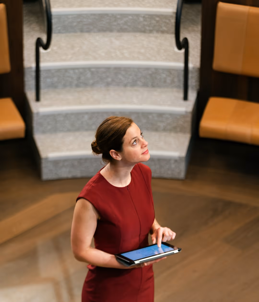 A person of a woman standing in a middle of a room while holding a tablet