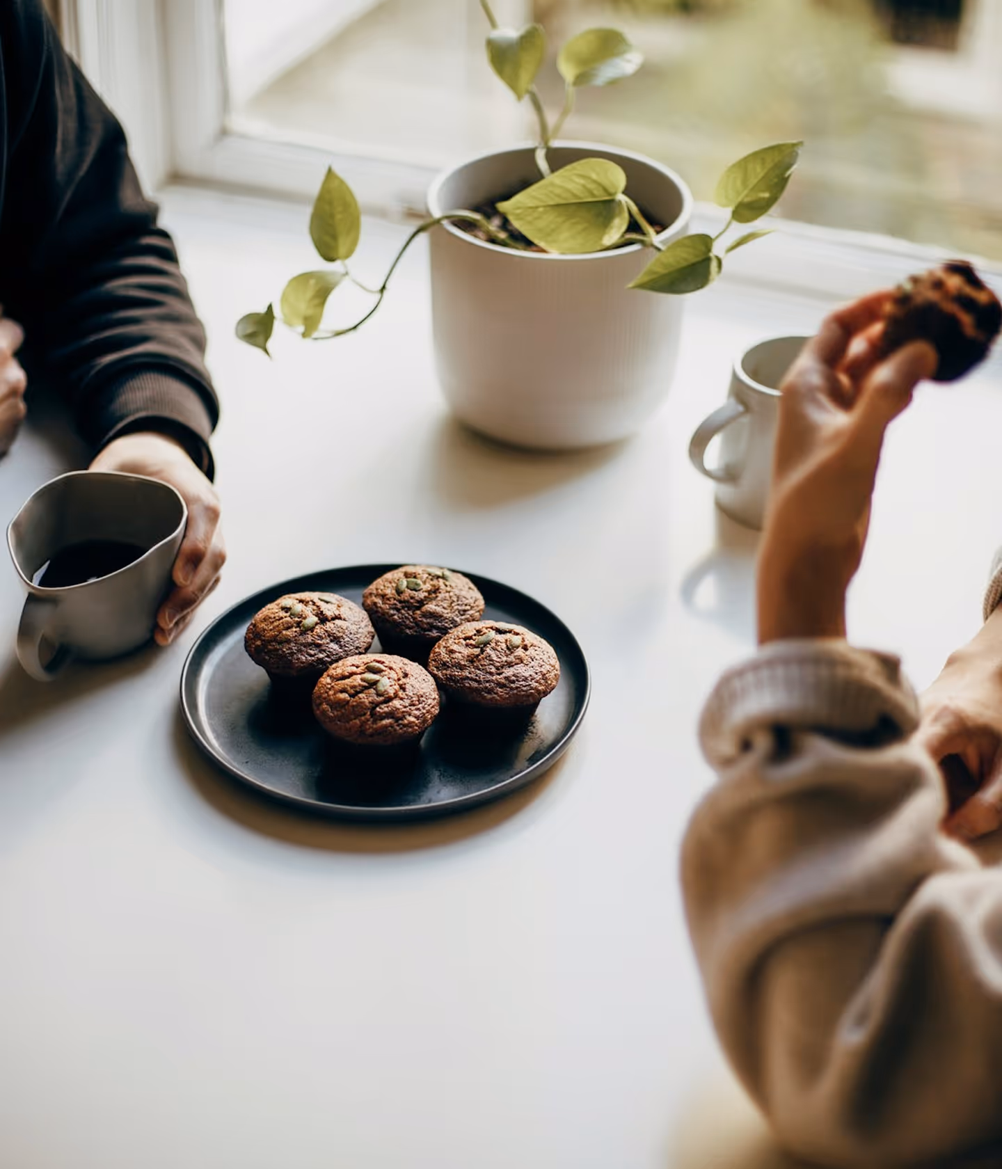 Two people eating muffins in the table