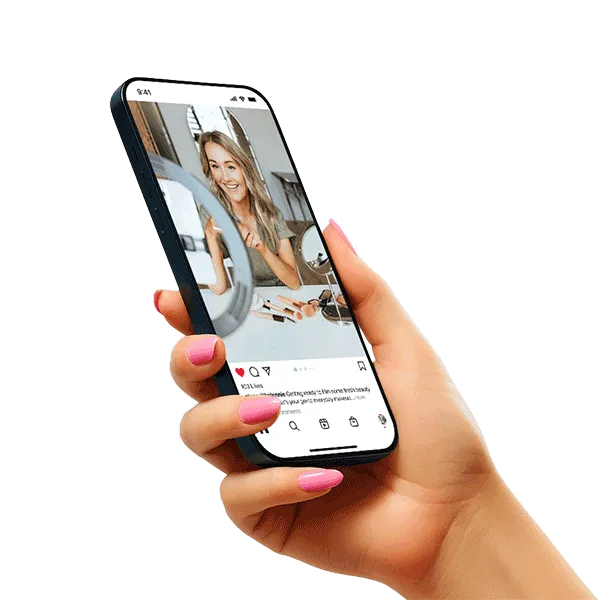 Hand with pink nail polish holding smartphone displaying an Instagram post of a smiling woman applying makeup.