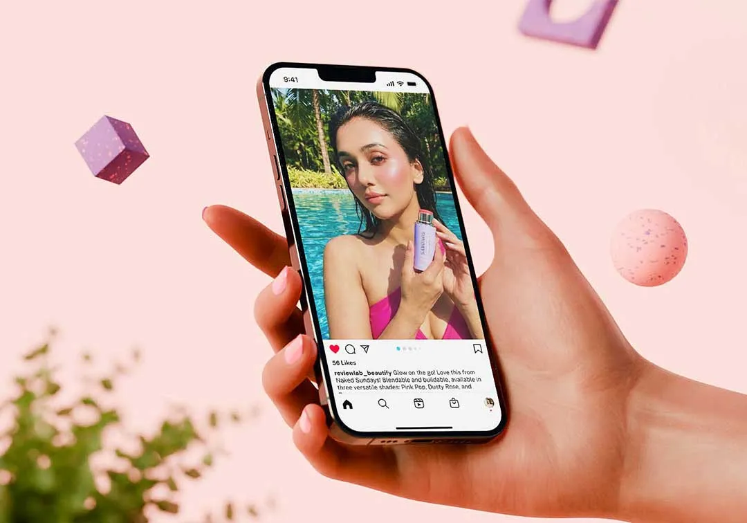 Hand holding a smartphone displaying an Instagram post of a woman in a pink top by a pool, holding a cosmetic bottle.