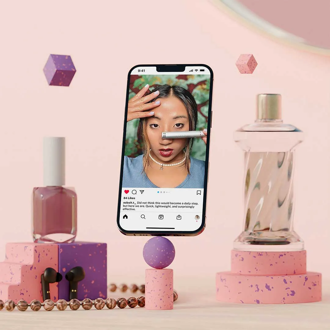 Smartphone showing a woman demonstrating a beauty product, surrounded by nail polish, perfume bottle, earphones, and geometric shapes on a light pink background.