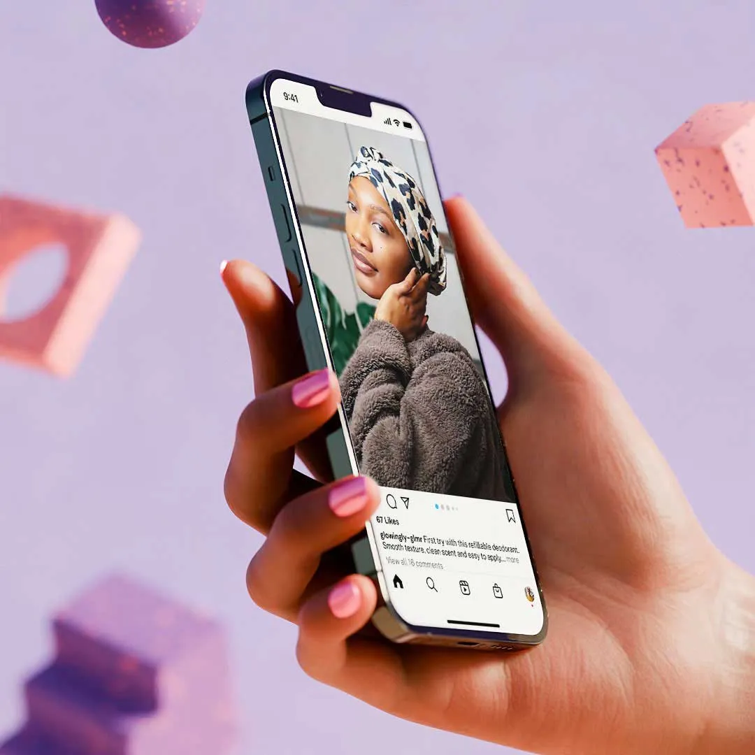Hand with pink nail polish holding a smartphone displaying an Instagram post of a woman wearing a leopard print headscarf and a cozy brown sweater.