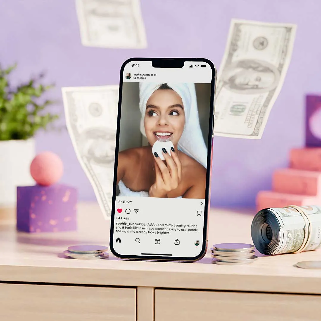 Smartphone displaying a skincare social media post with a smiling woman holding a white beauty device, surrounded by floating dollar bills and coins on a wooden surface.