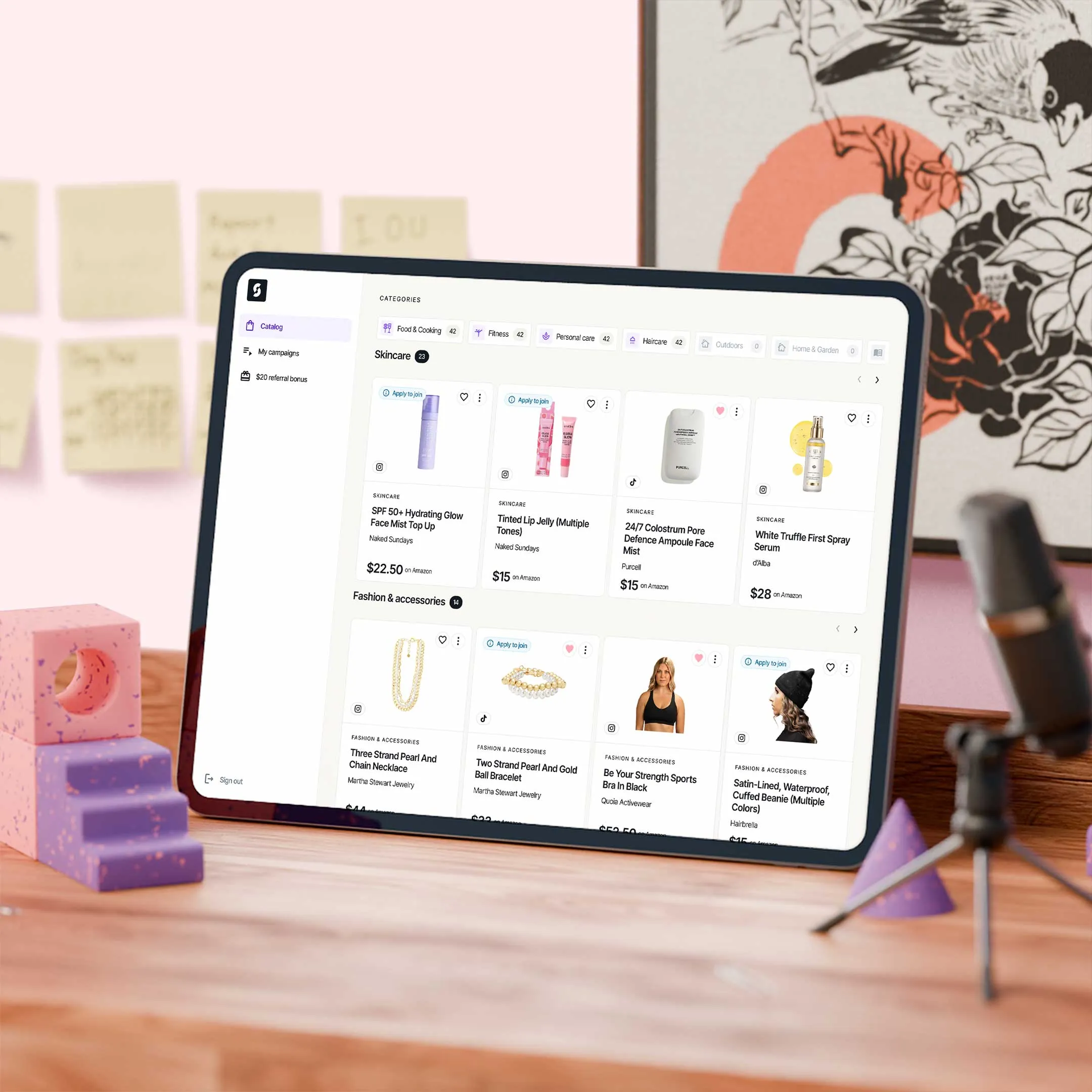 Tablet on wooden desk displaying an online marketplace of skincare and fashion accessories with product images, names, and prices.
