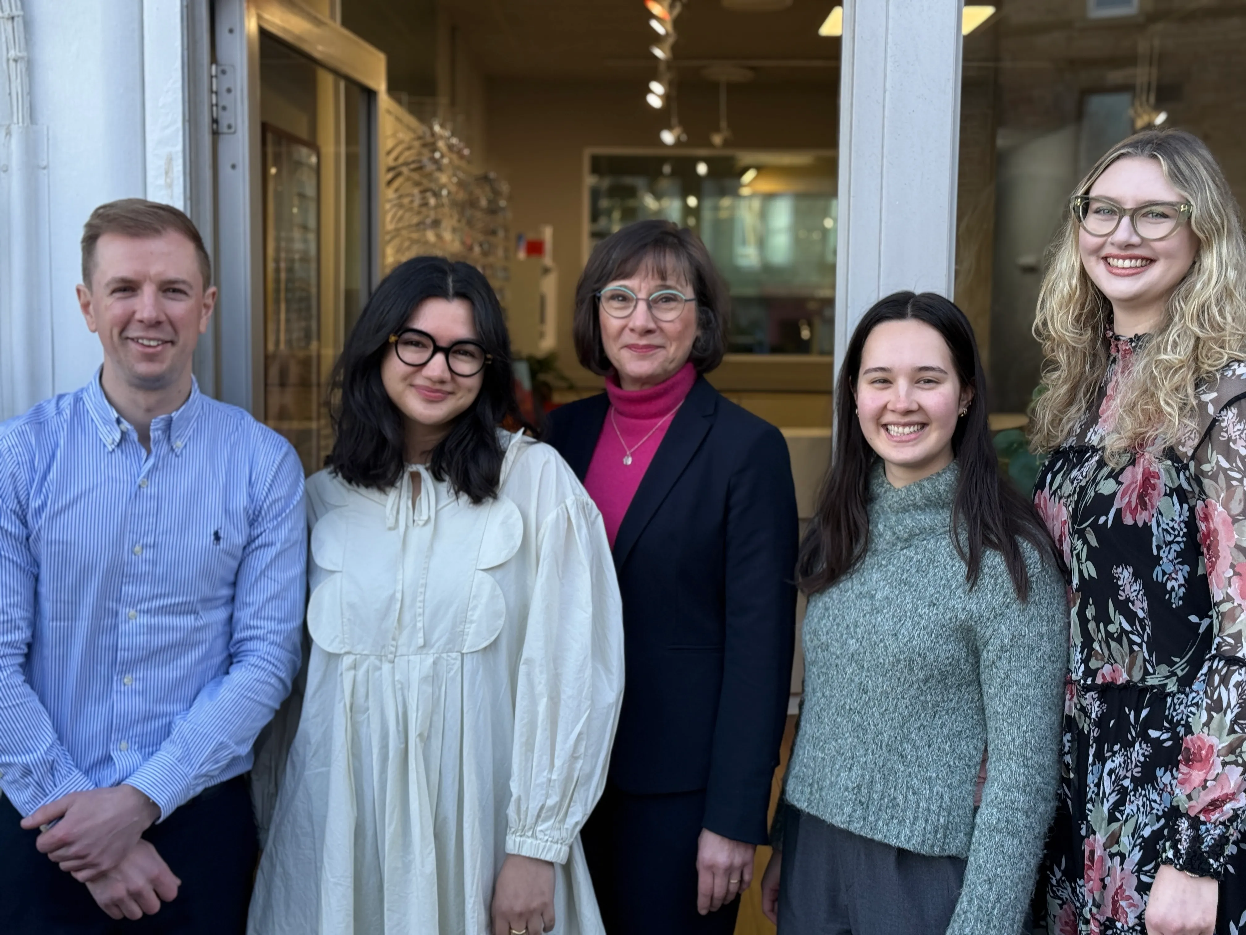 Five professionals smiling together in an office doorway