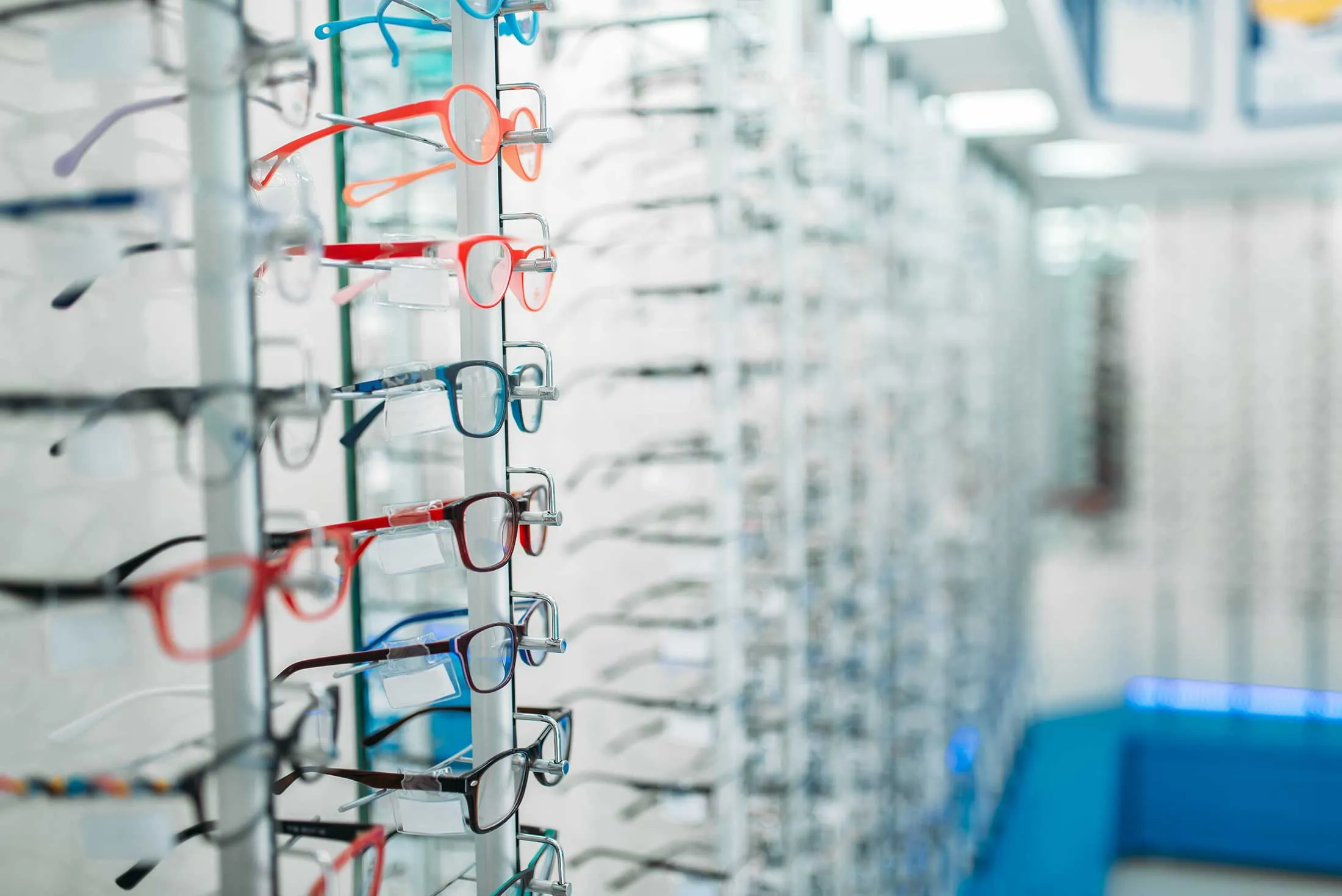 Colorful eyeglasses displayed on metal rack in optical store