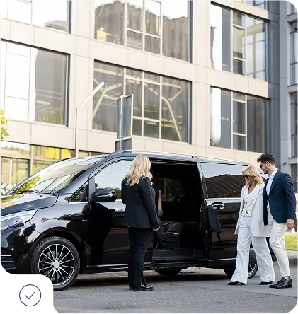Private taxi service in Vail Colorado – professional driver assisting couple into black minivan near modern building