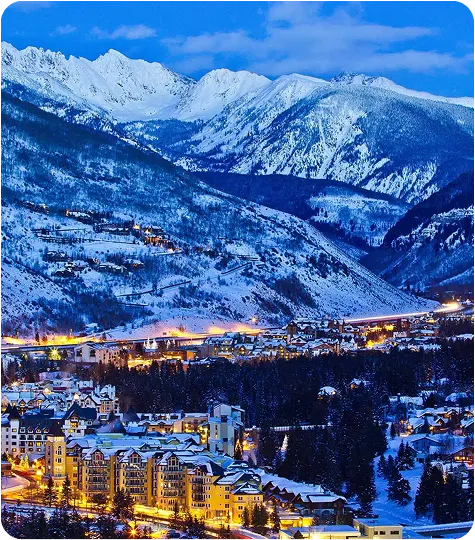 Winter evening view of Vail, Colorado with snow-covered mountains and ski resort lights