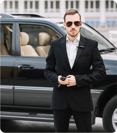 Professional private driver in black suit standing beside luxury SUV in Aspen Colorado