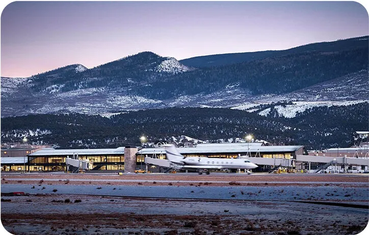 Private jet at Aspen Pitkin County Airport with snow-covered Colorado mountains in the background at sunrise