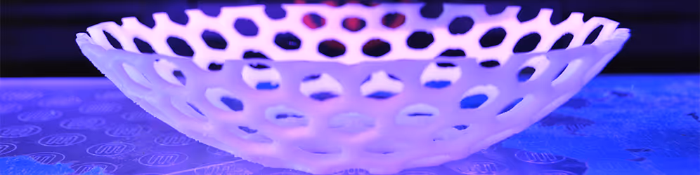 A young woman working in a machine shop. She is looking directly towards the camera, and is surrounded by men.