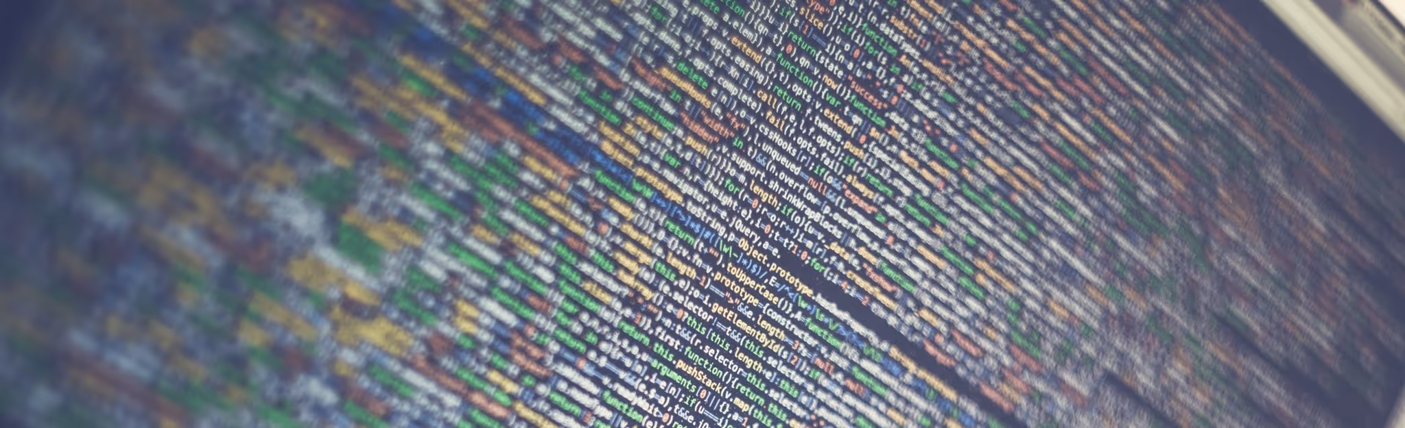 A young woman working in a machine shop. She is looking directly towards the camera, and is surrounded by men.