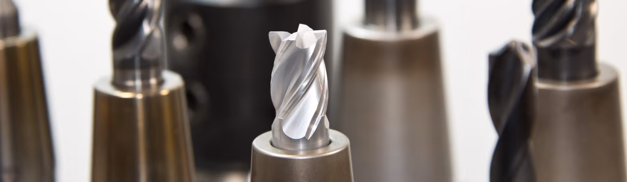 A young woman working in a machine shop. She is looking directly towards the camera, and is surrounded by men.