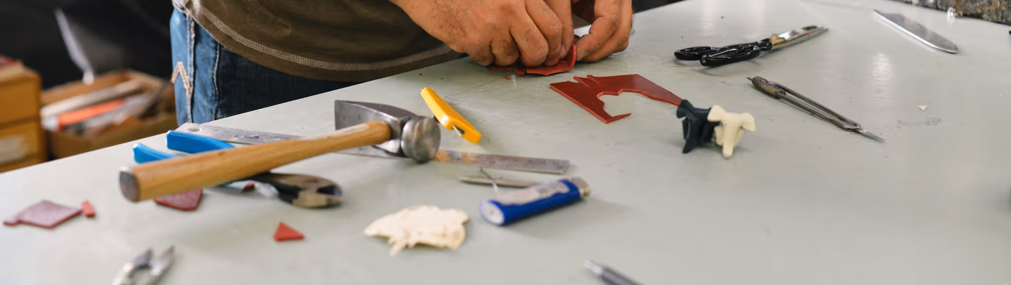 A young woman working in a machine shop. She is looking directly towards the camera, and is surrounded by men.