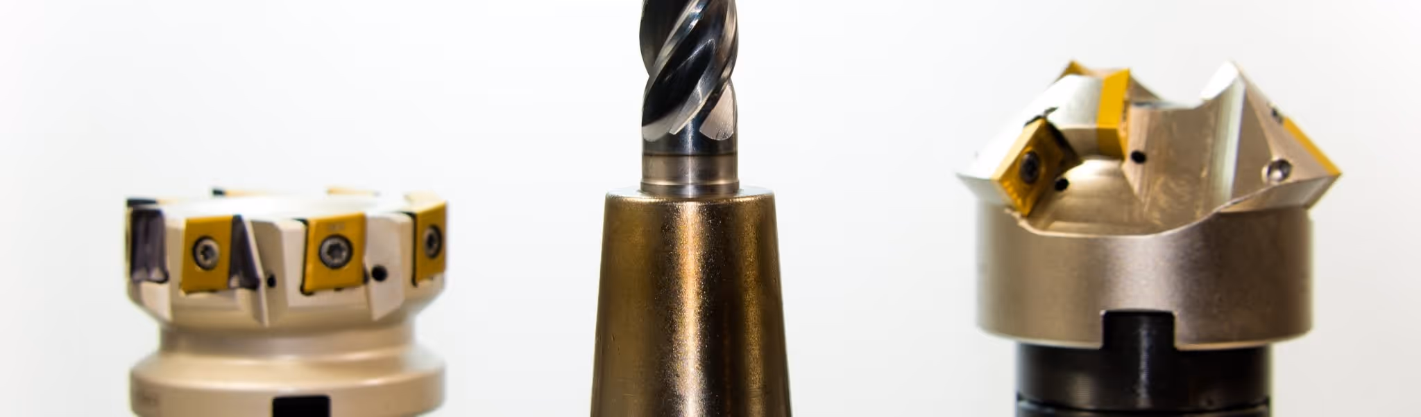 A young woman working in a machine shop. She is looking directly towards the camera, and is surrounded by men.