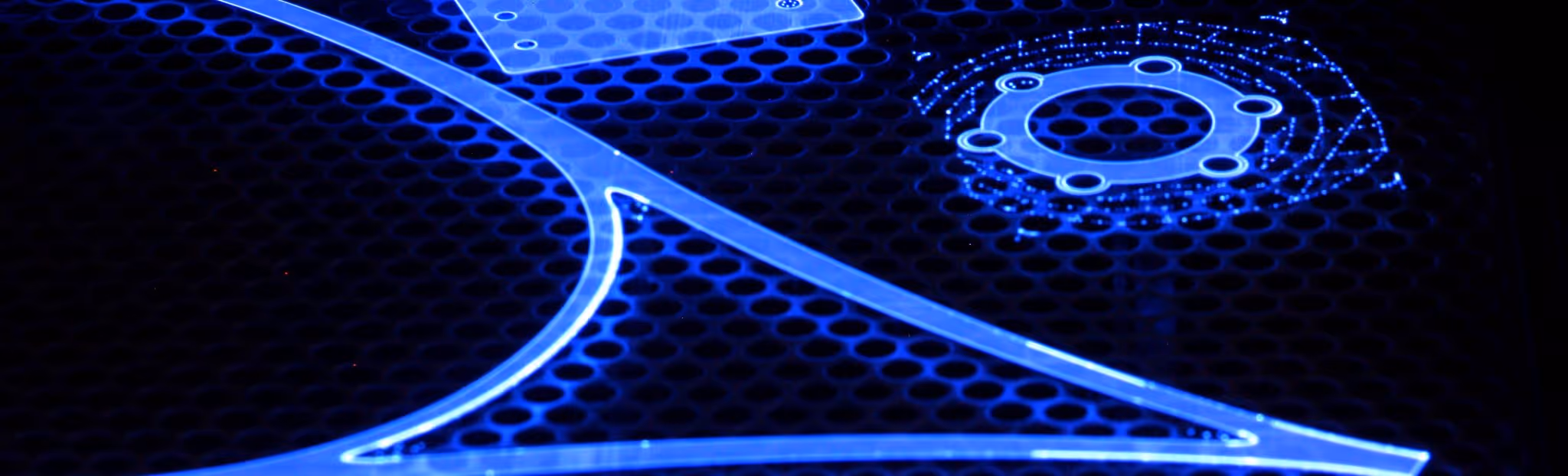 A young woman working in a machine shop. She is looking directly towards the camera, and is surrounded by men.