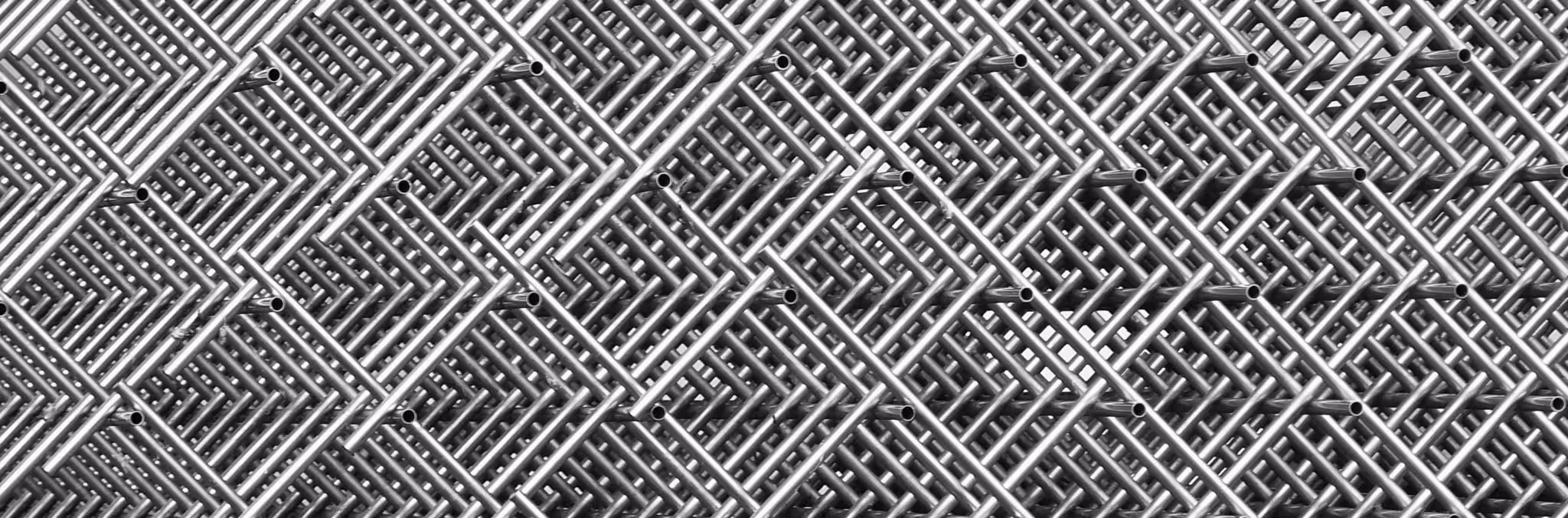 A young woman working in a machine shop. She is looking directly towards the camera, and is surrounded by men.