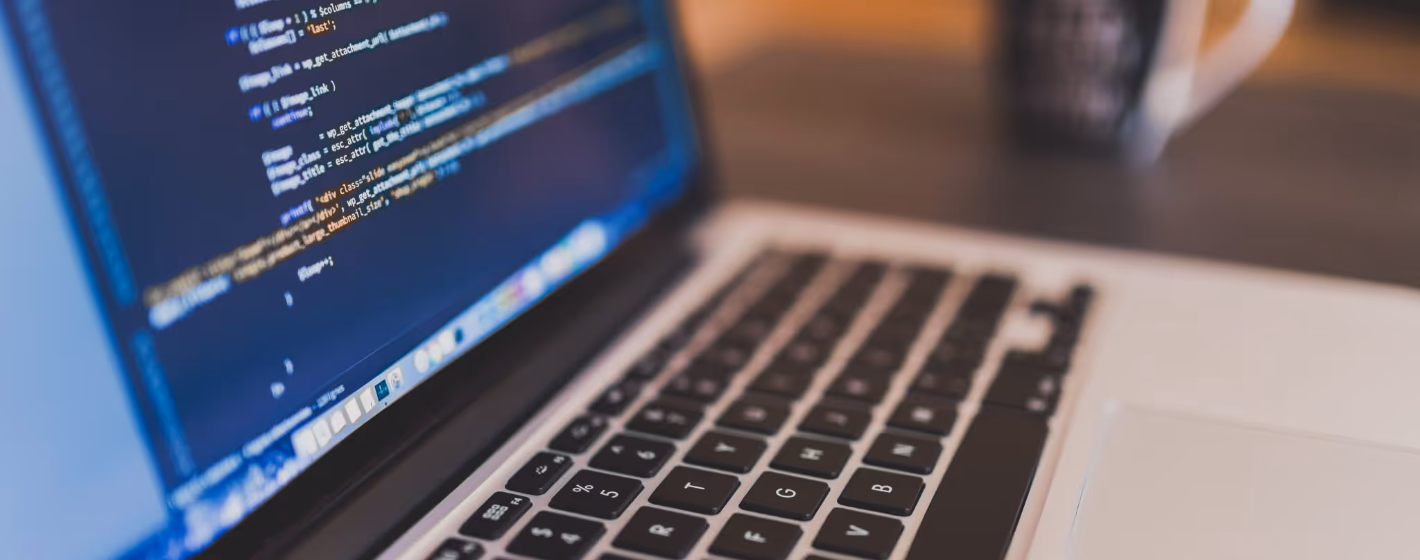 A young woman working in a machine shop. She is looking directly towards the camera, and is surrounded by men.